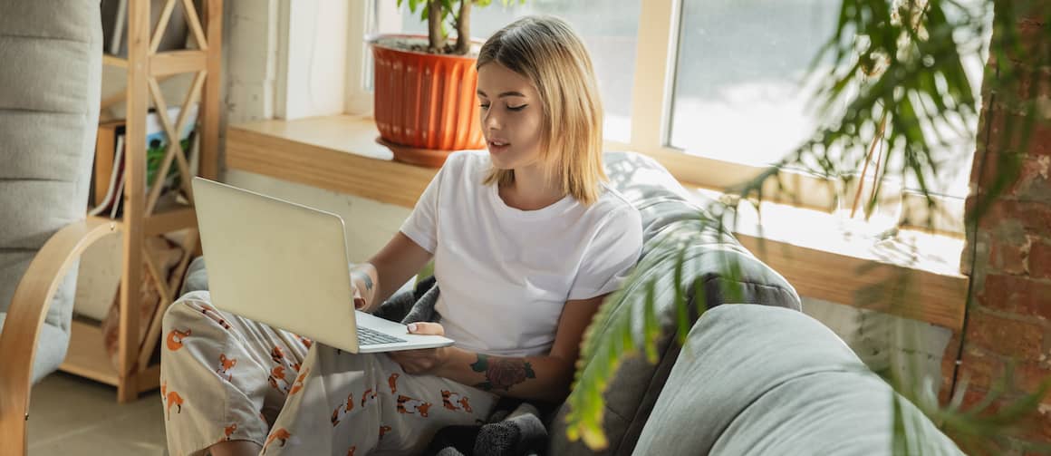 Woman relaxing at home while using her laptop on the couch.