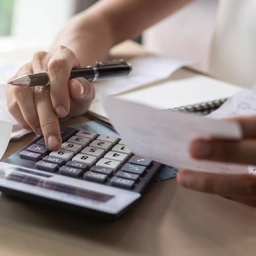 Close up of a person calculating bills with calculator.
