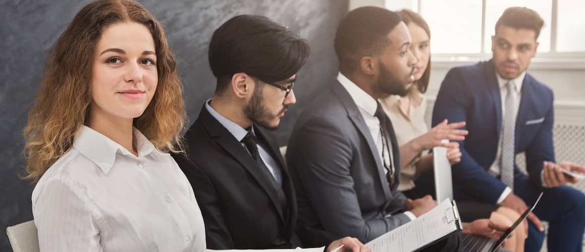 Woman sitting with other job applicants in a waiting room.