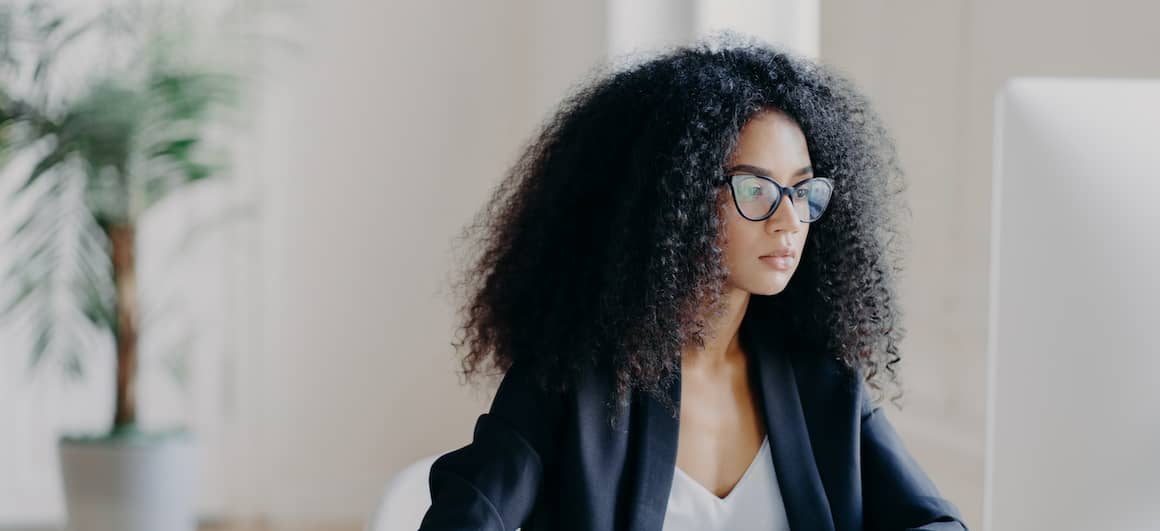 An African American woman with glasses using a computer, possibly working in the real estate or mortgage industry.