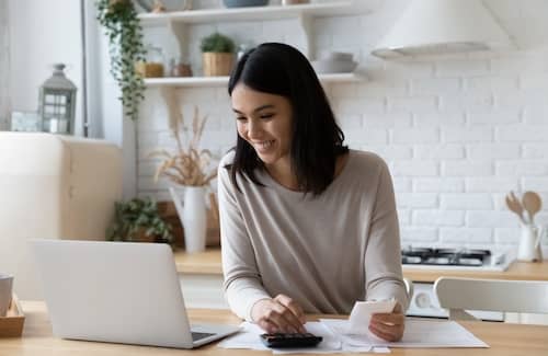 A young woman going over finances at her kitchen counter.
