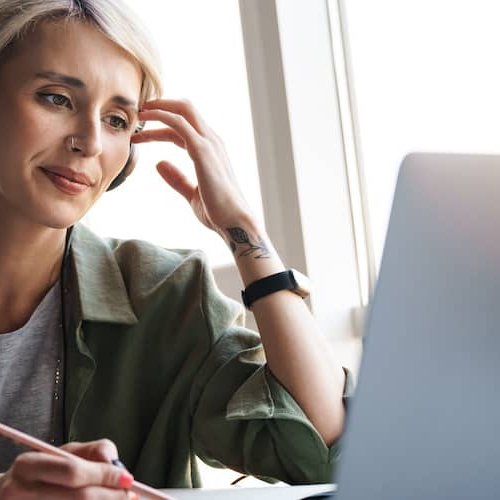 A woman with headphones on a computer, possibly working or relaxing at home.