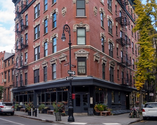 NYC street corner with old-fashioned brick apartment building.
