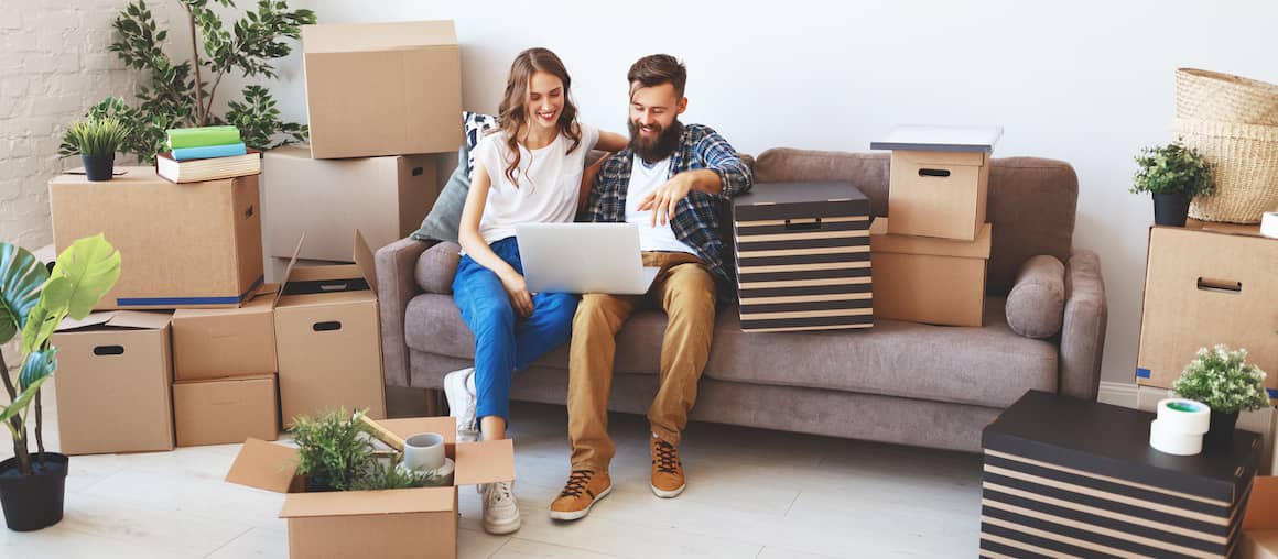 A happy couple moving into their new place surrounded by boxes.