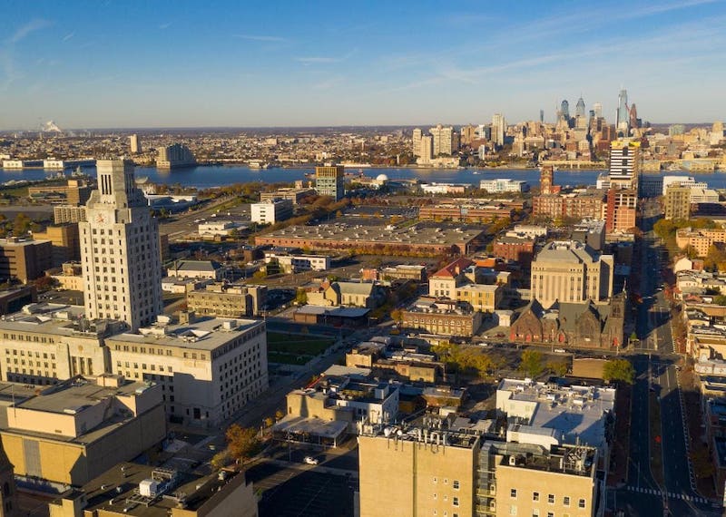 Aerial view of town with mix of new and historical tall buildings with large body of water in distance.