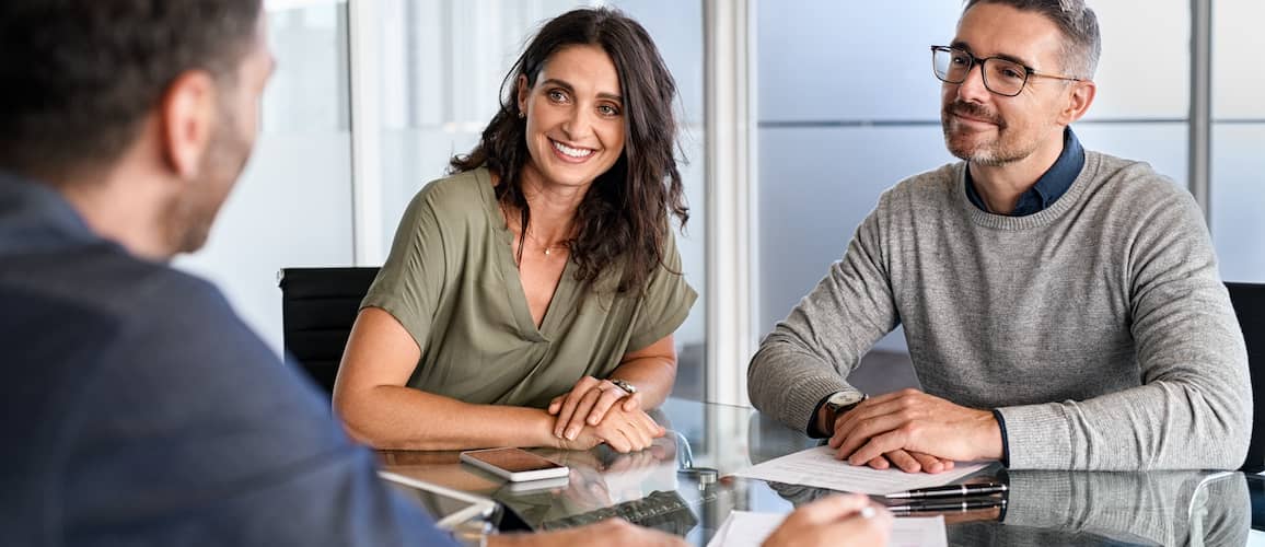 A couple reviewing documents with an advisor or financial professional.