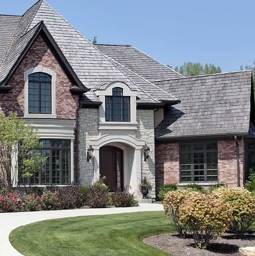 Large white two story house with porch atop a vast green lawn.