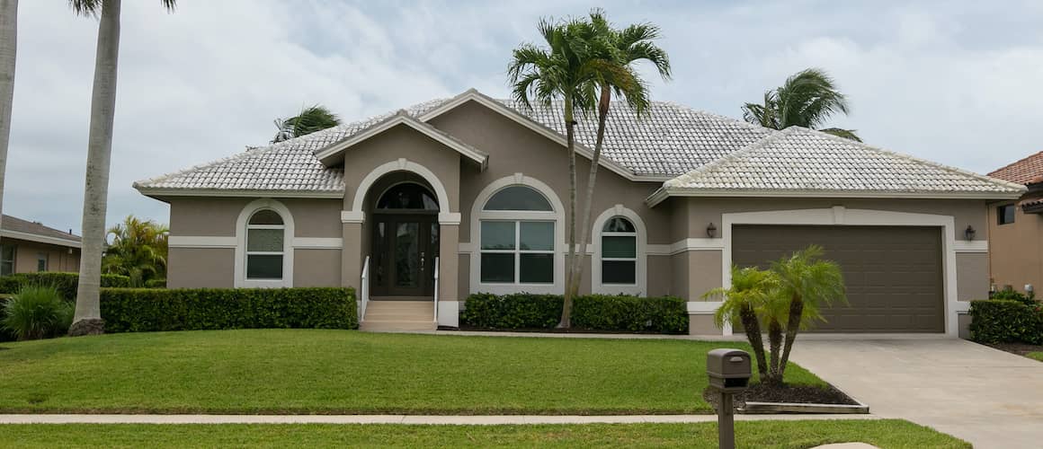 A grey-tan home in a tropical climate with a palm tree, suggesting a serene living environment.