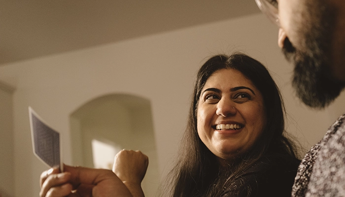 Man holding up playing card and woman laughing.