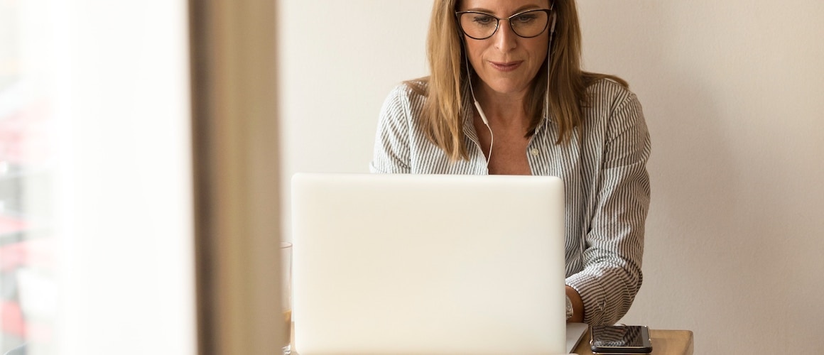 Image of woman looking down on computer, tackling her debt payment plan.