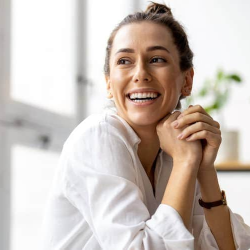 A woman smiling at a desk, radiating positivity and contentment.