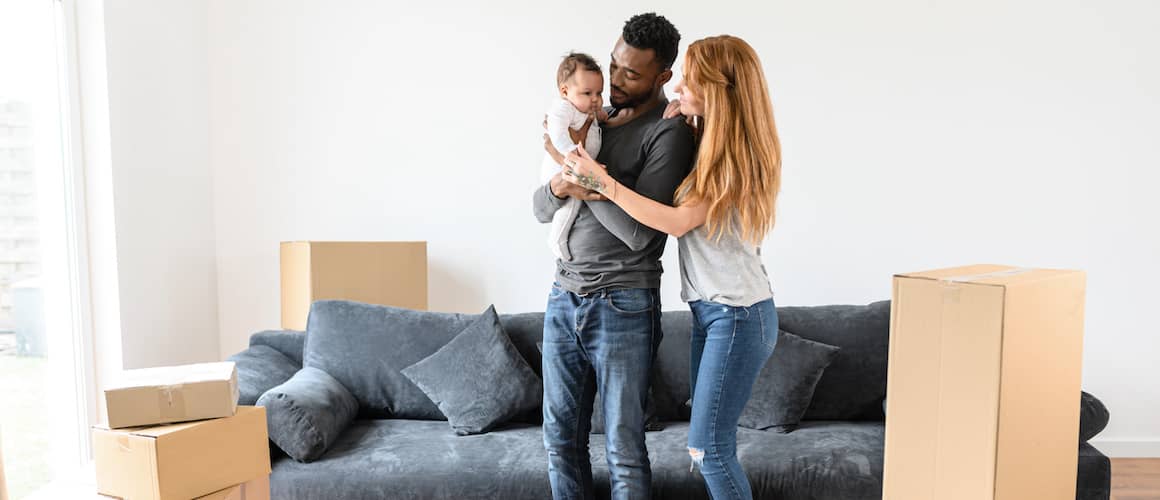 A couple with a baby in a new home, symbolizing the joy of starting a family in a new place.