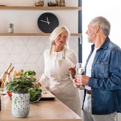 Two couples in a kitchen discussing something.