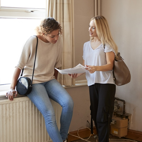 Two females looking into the paper work potentially for an apartment or house.