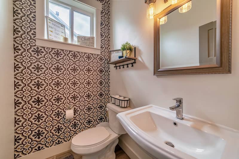 Half bathroom with patterned wallpaper on one wall.