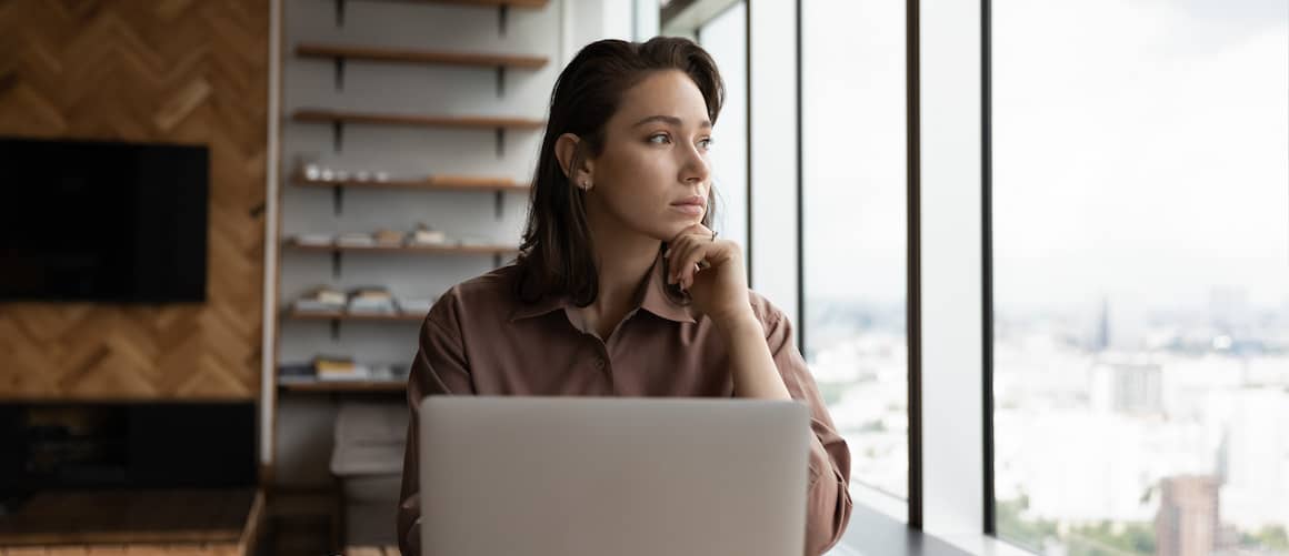 A woman looking out a window, possibly pondering or reflecting.