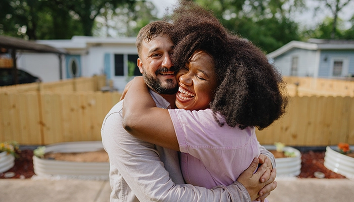 Woman and man smiling, laughing, and embracing each other.