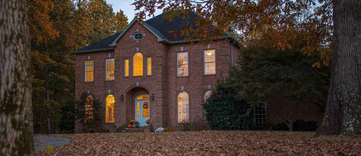 A red brick colonial home in fall, depicting a colonial-style house in an autumnal setting.