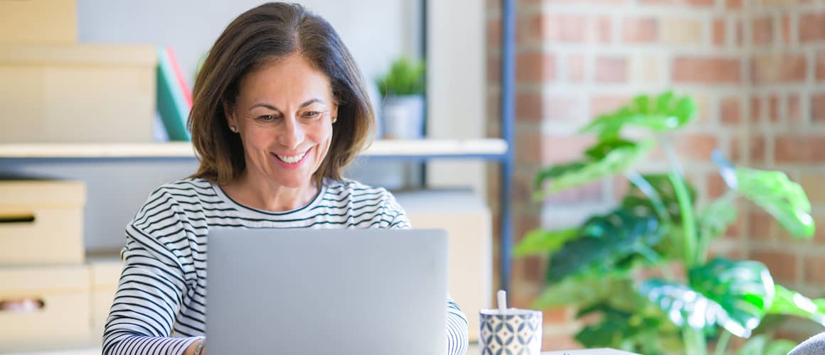 Older woman using her laptop at home and smiling.