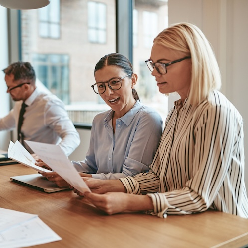 Two businesswomen looking at paperwork in an office.