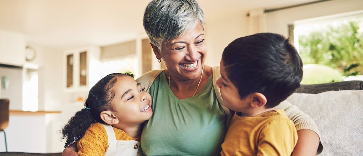 Smiling grandmother holding both her granddaughter and grandson.