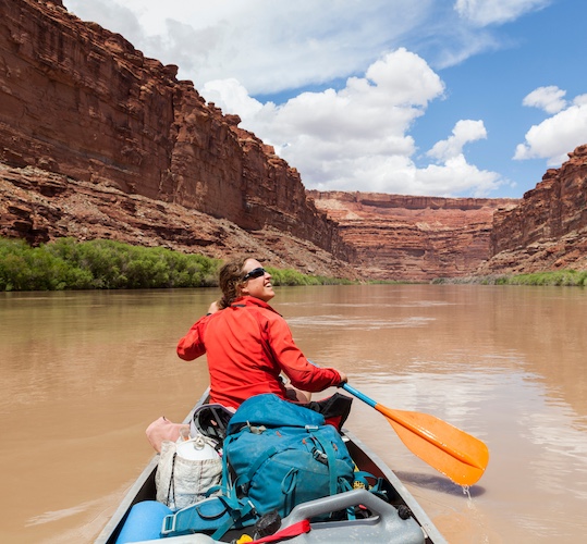 Woman paddling her canoe down a river.