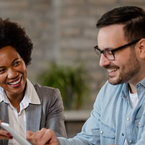Real estate agent pointing to listings on tablet as he discusses options with hopeful couple seeking to purchase a home.