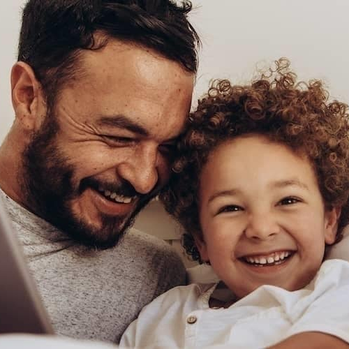 A father and son having a moment and watching something on the tablet.