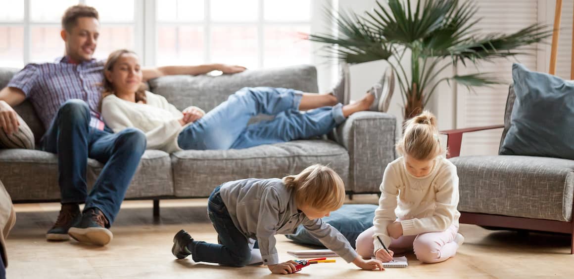 Family gathered together relaxing in living room of home.