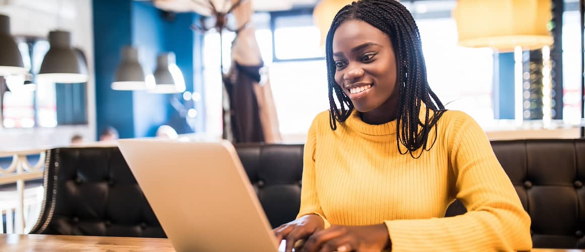 African American woman with laptop and phone in a cafe