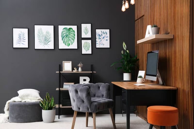 Home office with wood paneled wall, dark grey accent wall and grey velvet tufted office chair.