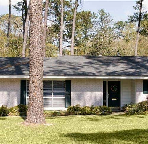 A rambler house with a white brick exterior, showcasing a single-story residence with a clean and classic design.