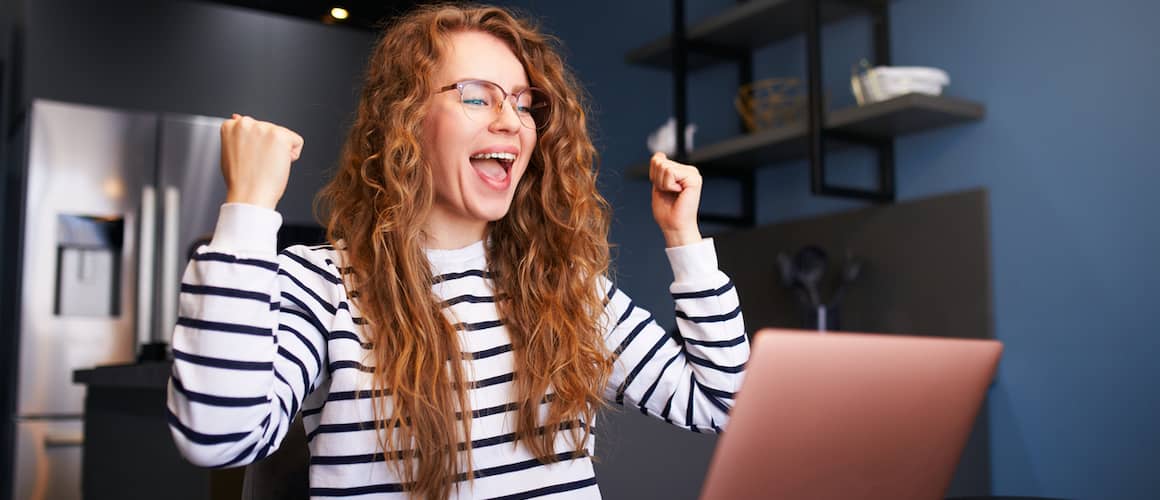 Happy woman checks e-mail, good news about success on laptop