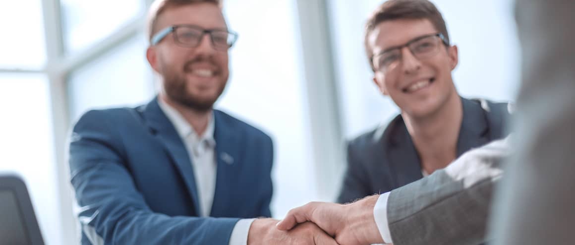 Smiling businessmen shaking hands, symbolizing a successful business deal or partnership.