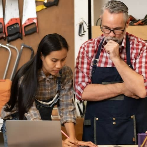 Woman describing plans for carpentry design to man who focuses intently.