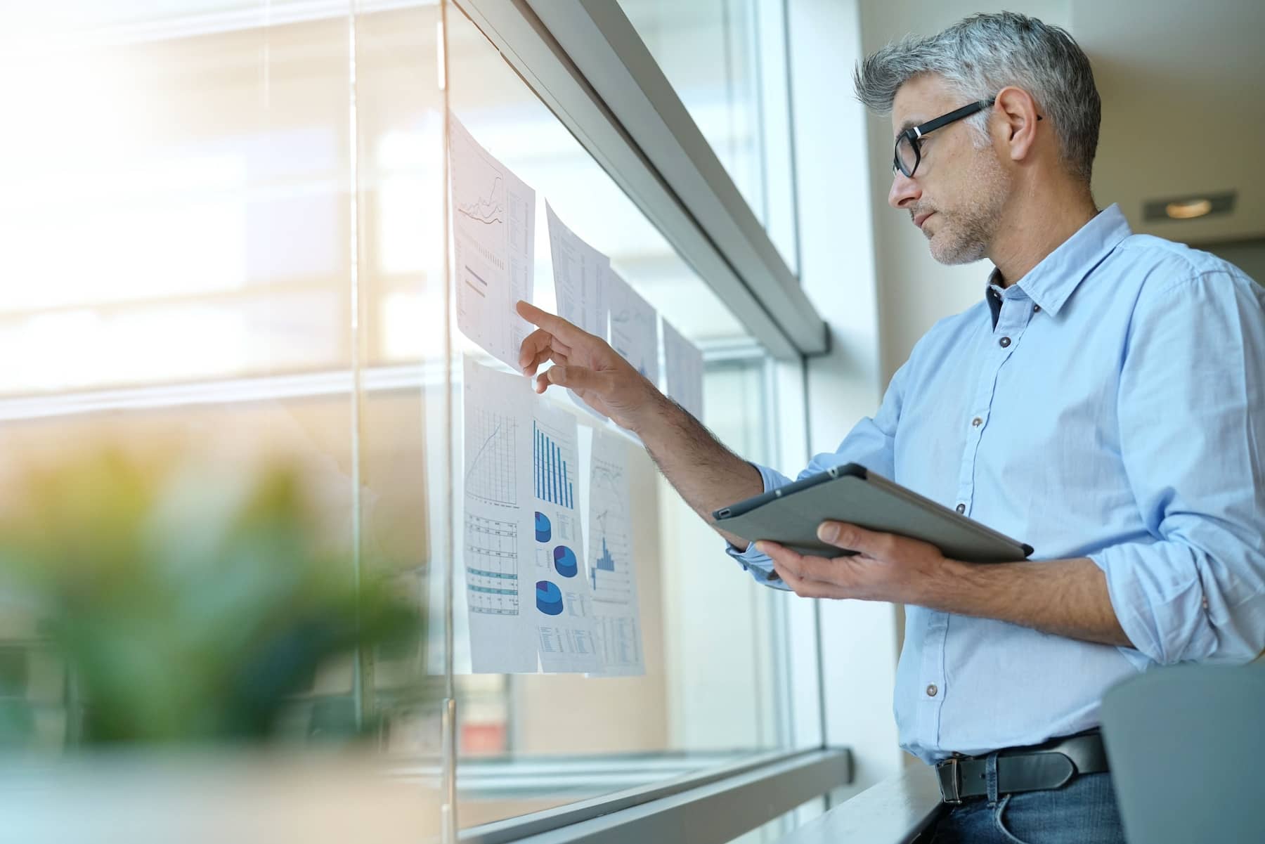 businessman looking at charts on office window