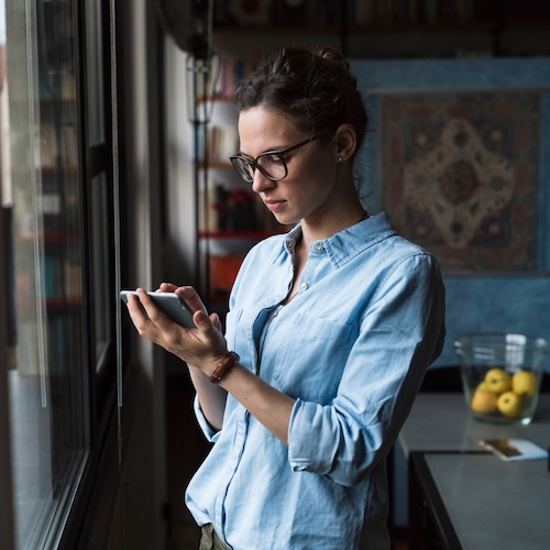 Woman looking at phone with a contemplative expression.