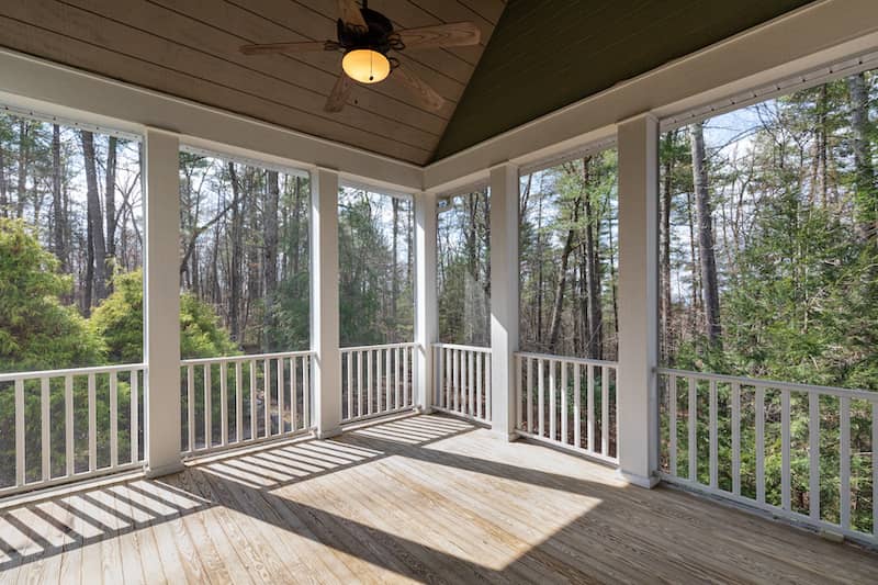 Screened porch looking out over densely wooded area.