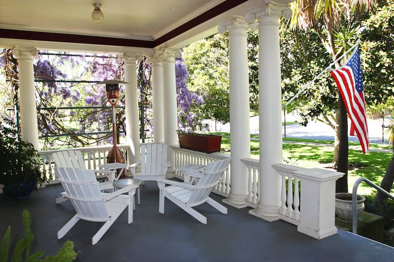 RHB Assets From IGX: Front porch with inviting furniture, potted plants, and a porch swing.