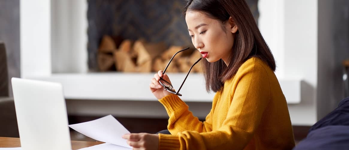 A woman in a yellow cardigan with documents, suggesting paperwork or documentation in real estate.