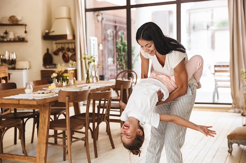 Mother and daughter playing in kitchen of home.