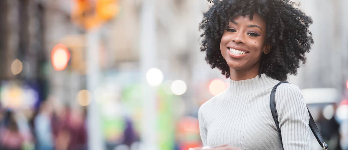 Gen Z woman smiling walking in her city.