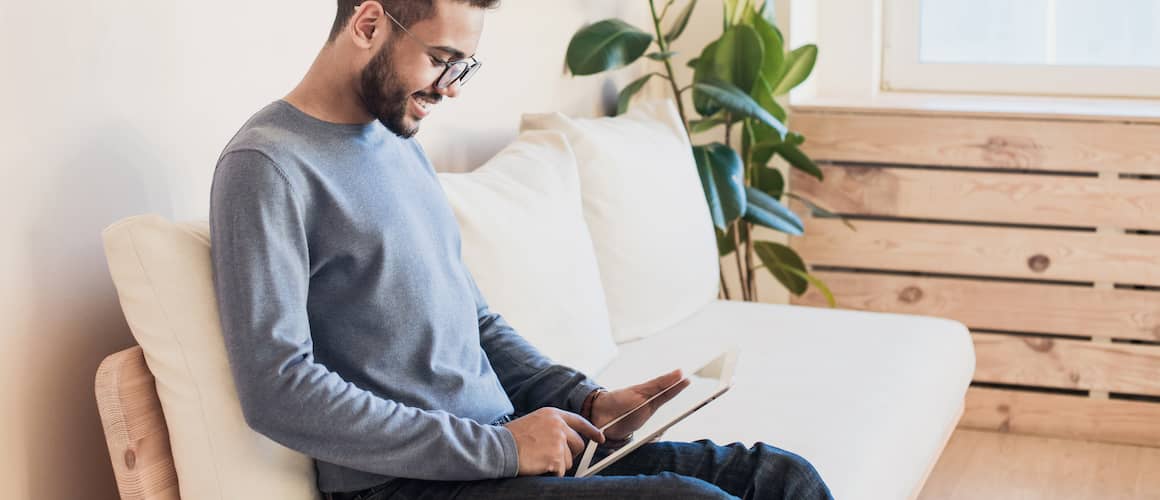 Image of man making monthly loan repayment on couch.