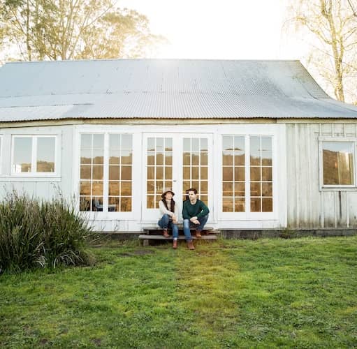 Ranch style barndominium with white roof and white siding. Three french doors are in the center and flanked by additional windows  on either side.