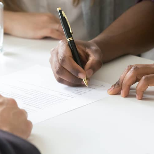 A man signing a home document with a broker, depicting a real estate transaction.