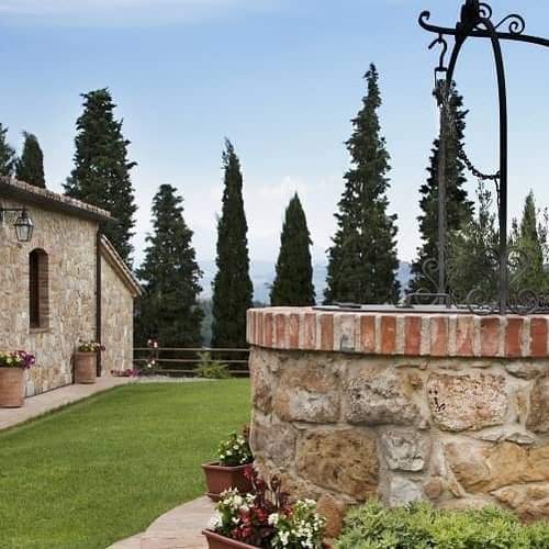 A well in front of a house, adding a rustic and traditional touch to the property's exterior.