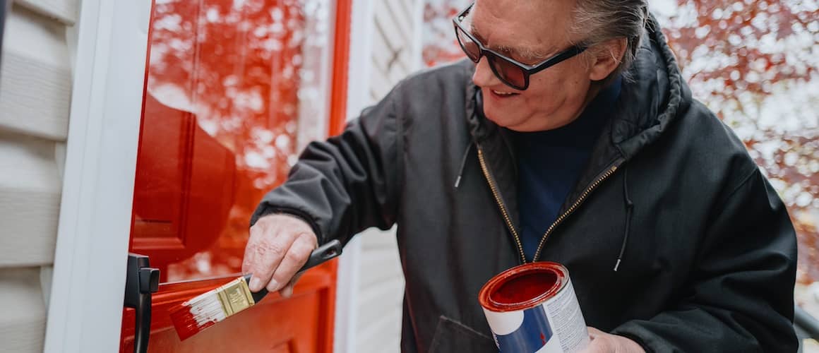 Man painting front door of home red.