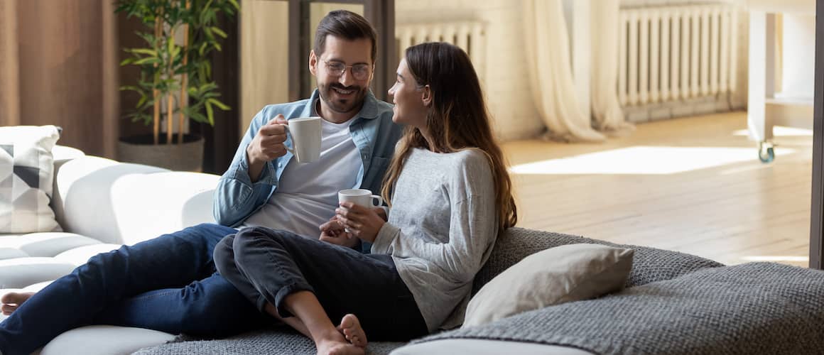 RHB Assets From IGX: Smiling couple cozy on a couch with a blanket, enjoying a movie night at home.