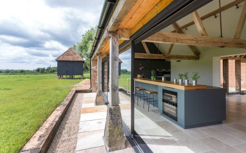 Barndominium with large open sliding doors looking into the kitchen on the right with a view of the elevated gray shed on the left. 