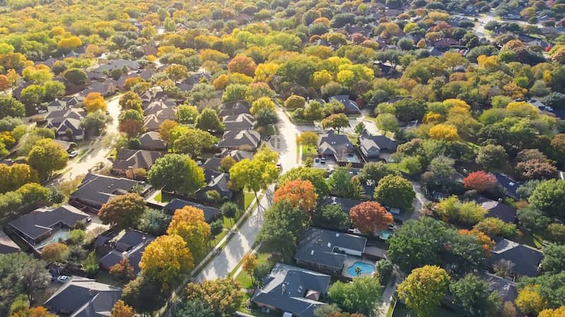 Lush greenery master planned community subdivision colorful fall leaves and row of single-family homes with swimming pool in upscale neighborhood Dallas, North Texas